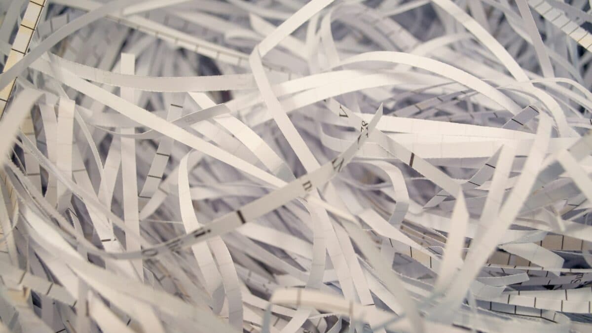 Tas de papier blanc déchiqueté en fines lamelles sur une table, illustrant une destruction sécurisée de documents.