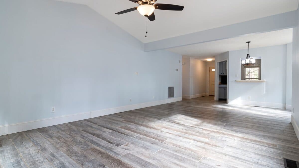 Salon vide, lumineux et propre avec parquet, illustrant un logement redevenu sain et habitable.