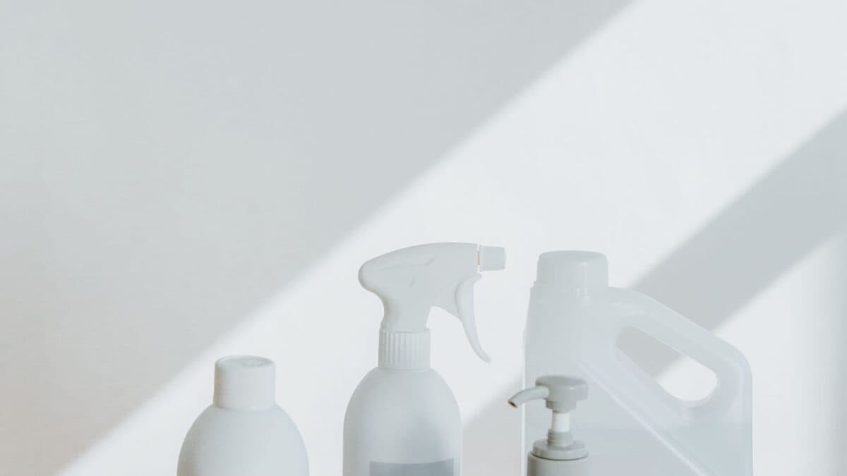 Produits de nettoyage et flacons disposés sur une surface claire, prêts pour une décontamination de logement.