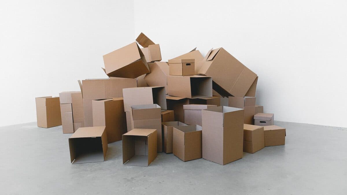 Cartons empilés au sol dans une pièce claire, prêts pour le tri et le rangement pièce par pièce.